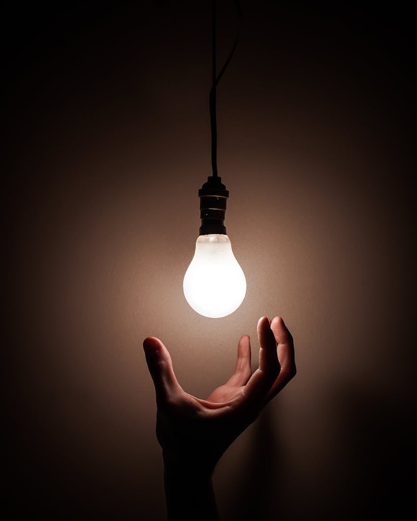 Main tenant une ampoule blanche, symbole d’idée claire et de compréhension en finance et investissement"