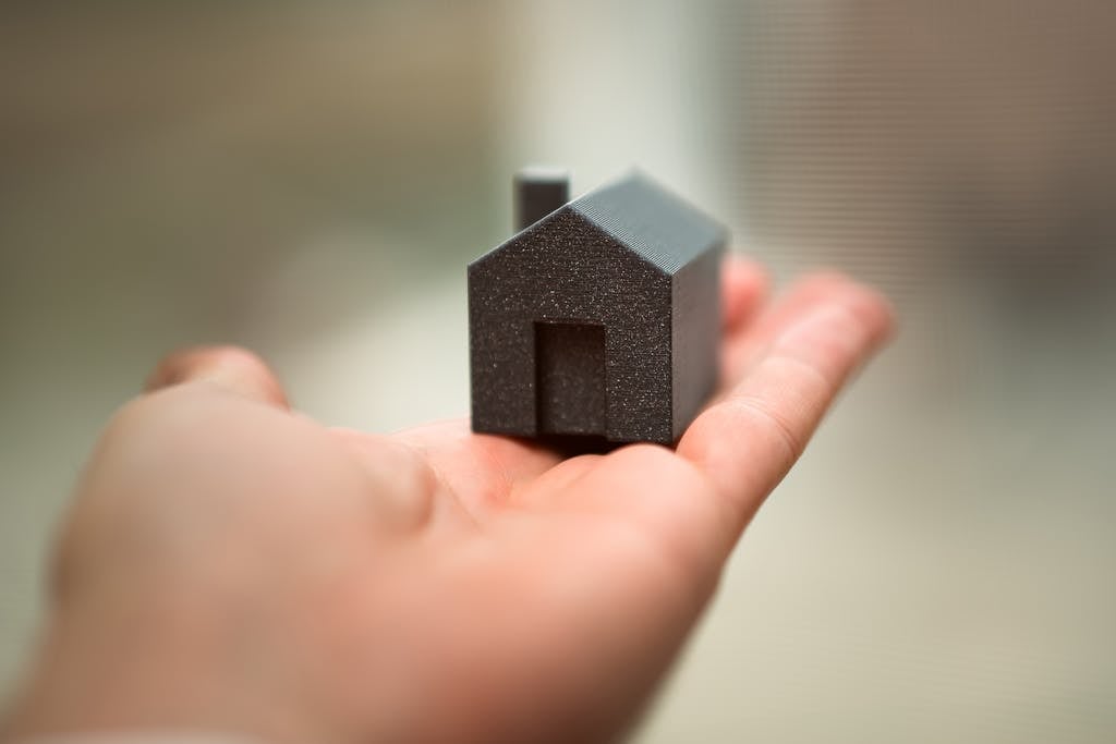 Maison miniature dans le creux d'une main représentant le concept d’investissement et de mise en location en immobilier