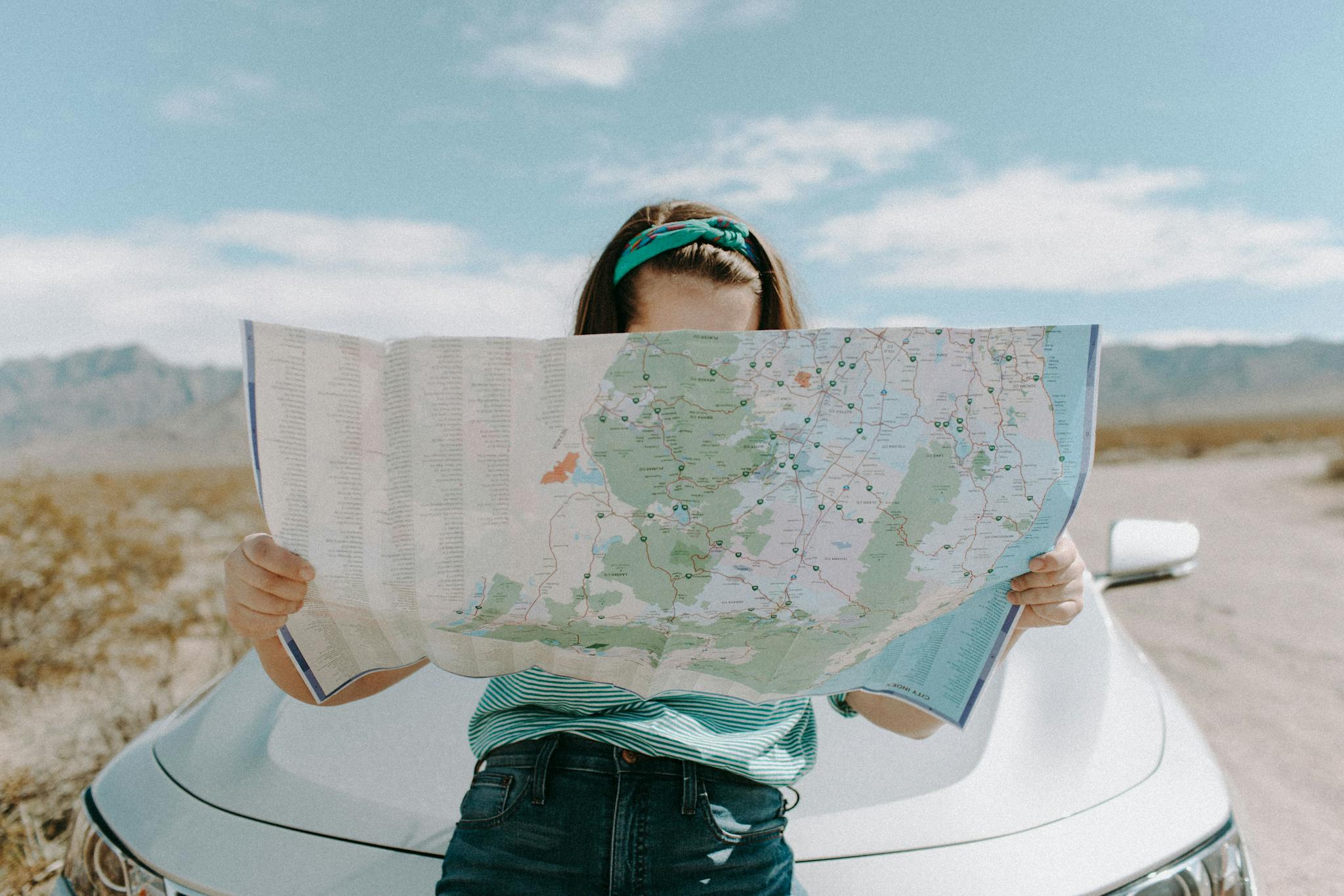 Une femme regarde une carte pour trouver son chemin dans un environnement désertique comme les étapes de ce guide qui aide les personnes à trouver leur propre chemin vers l'investissement en SCPI